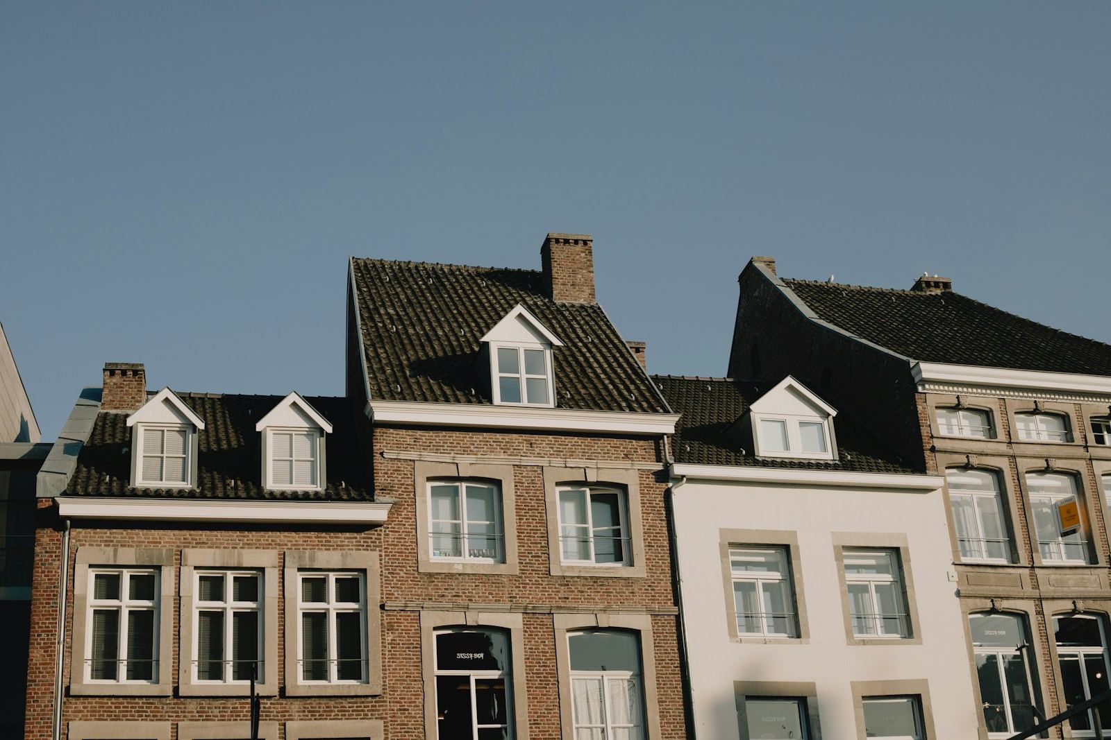 Rij woningen met bakstenen en witte gevels en dakkapellen