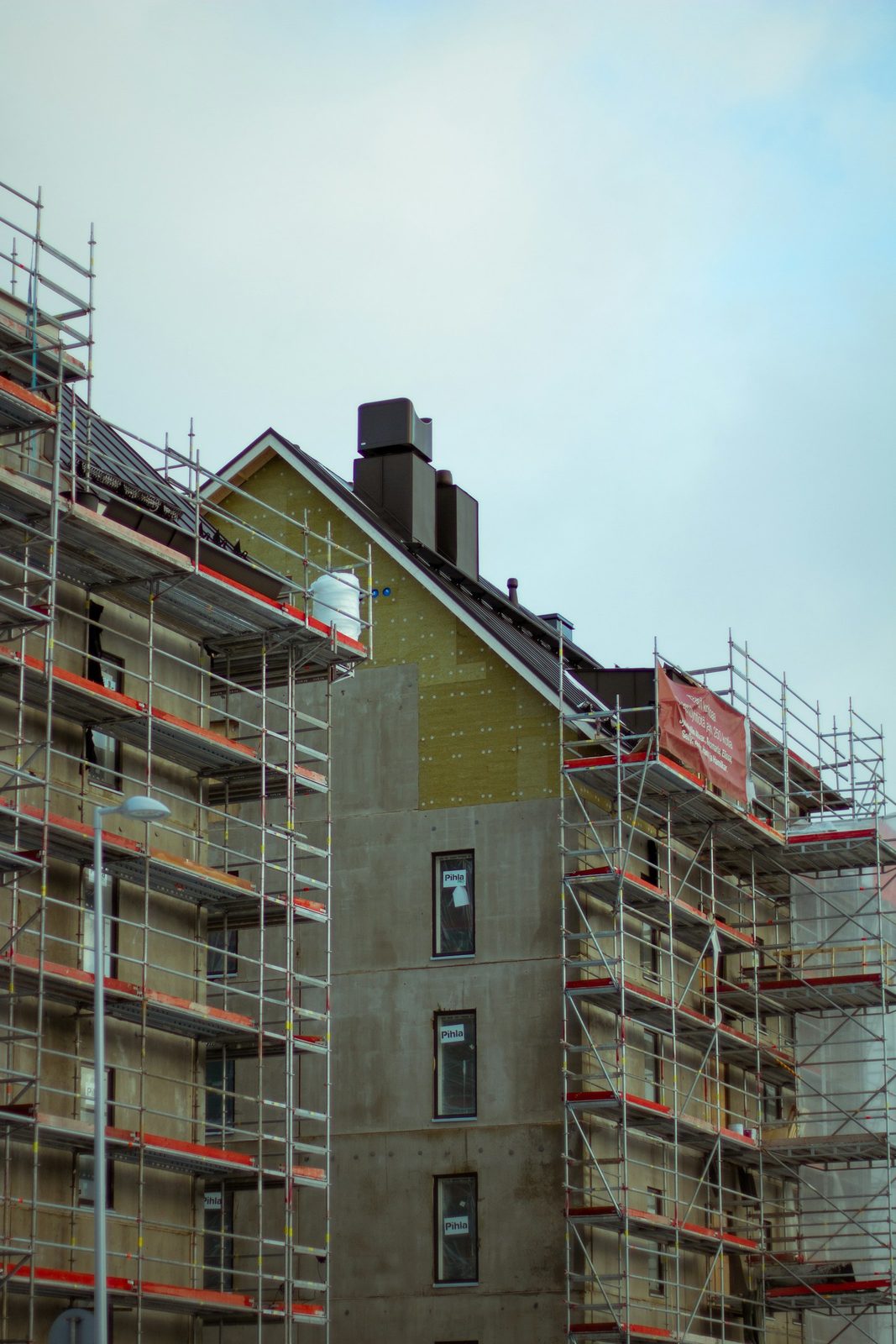 Appartementsgebouw in renovatie met stellingen en zichtbare isolatieplaten tegen de gevel